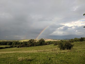 Scenic view of field against rainbow in sky