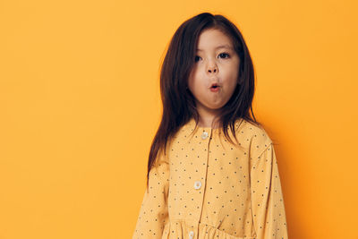 Cute girl making facial expression against yellow background
