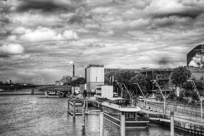 Bridge over river by buildings against sky