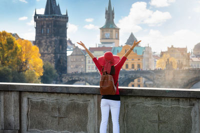 Rear view of woman with arms raised standing on bridge