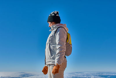 Side view of woman standing against clear blue sky during winter