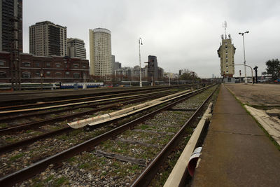 Railroad tracks by buildings in city against sky