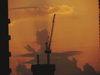 Silhouette factory against sky during sunset