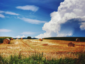 Hay bales on field against sky