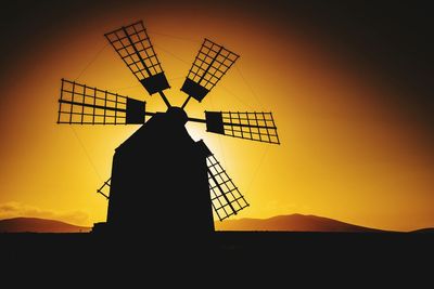 Low angle view of traditional windmill against sky during sunset