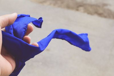 Cropped hand of person holding blue textile on road