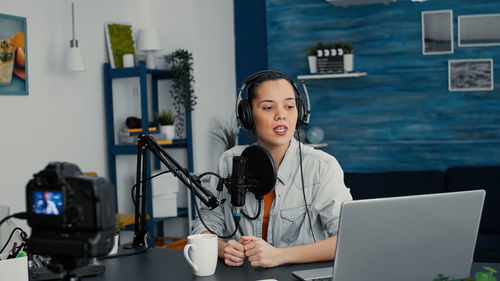 Portrait of young woman using digital tablet while standing in office