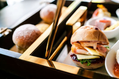 Mini hamburger with bun, sliced ham, cheese, lettuce and raspberry jam that served for afternoon tea