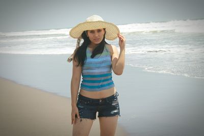 Portrait of young woman standing on shore at beach