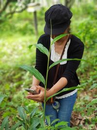 Woman holding plant while standing on field