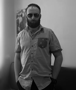 Portrait of young man wearing sunglasses standing against wall