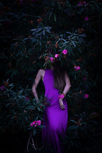 Rear view of woman standing by pink flowers on field