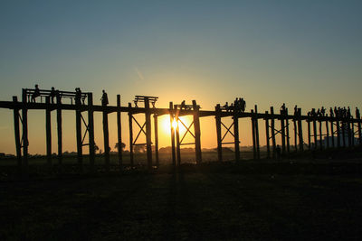 Silhouette poles on field against clear sky during sunset