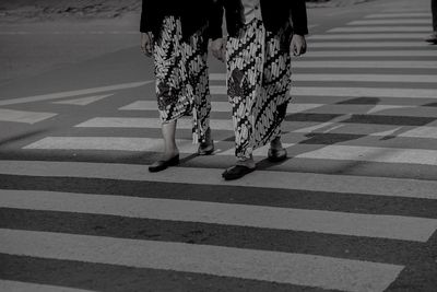 Low section of woman crossing road