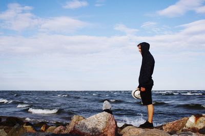 Full length of woman on rock at beach against sky