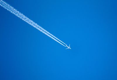 Low angle view of airplane flying against clear blue sky