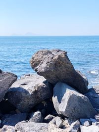 Rocks on beach against clear sky