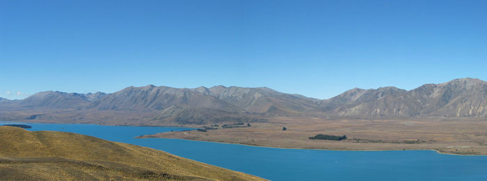 Scenic view of lake and mountains against clear blue sky