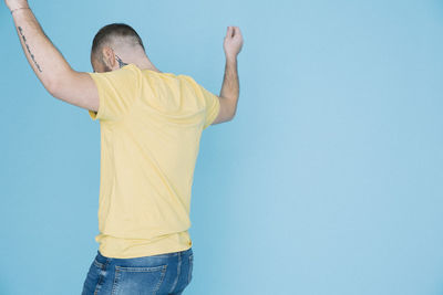 Rear view of man dancing against blue background