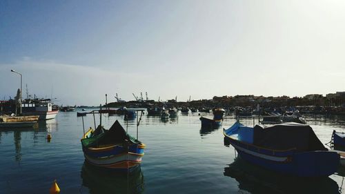 Boats moored at harbor against sky