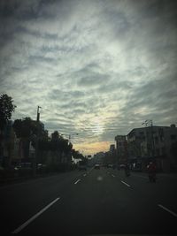 View of city street against cloudy sky