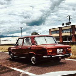 Cars on road against cloudy sky