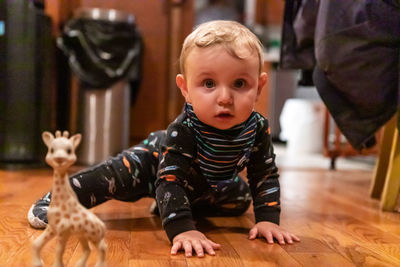 Cute boy playing on hardwood floor at home