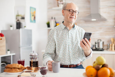 Front view of senior man using mobile phone on table