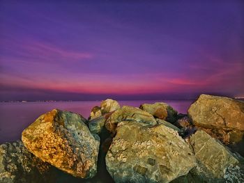 Rocks by sea against sky during sunset