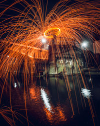 Firework display over lake against sky at night