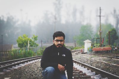 Young man standing on railroad track against sky
