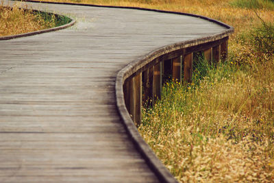 High angle view of boardwalk amidst grassy field