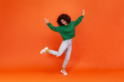 Full length of woman standing against yellow background