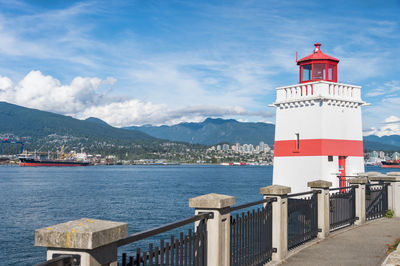 Lighthouse by sea against sky