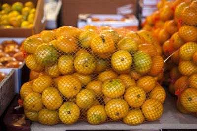 Close-up of tangerines in nets for sale at market stall