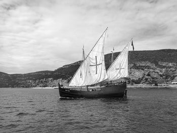 Sailboat on sea against cloudy sky