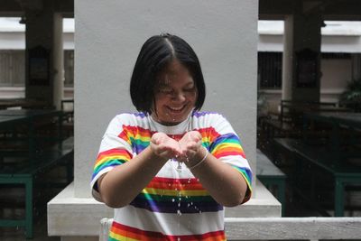 Smiling woman playing with water against wall