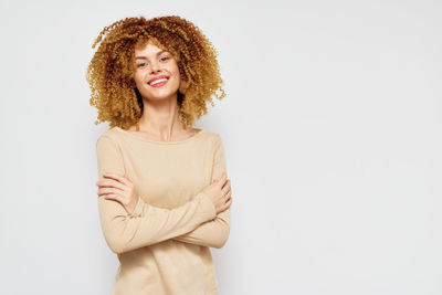 Portrait of young woman standing against white background