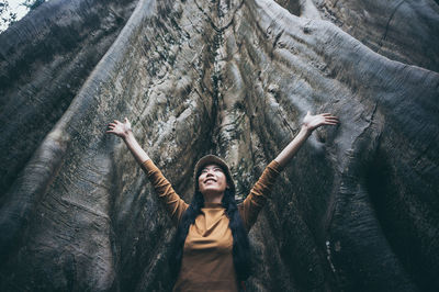 Young woman standing by tree trunk