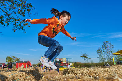 Pretty girl jumping over the hay stacks at a farm fair on halloween