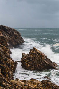 Scenic view of rocky beach by sea against sky