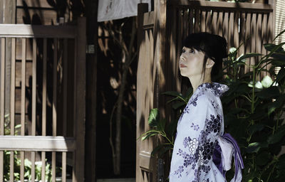 Woman in kimono looking up while standing in city