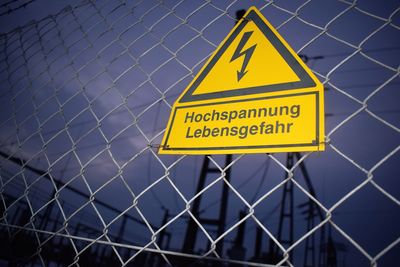 Close-up of warning sign on chainlink fence at dusk