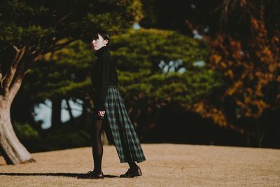 Side view of woman walking against trees