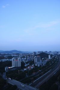 High angle view of buildings in city against blue sky