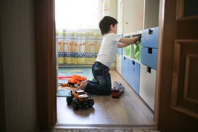Boy playing with toy cars in a child's room, the concept of childhood and safety