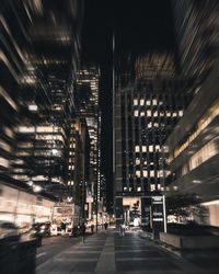 Illuminated street amidst buildings in city at night