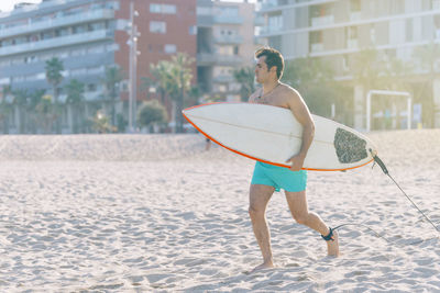 Man carrying surfboard while running at beach