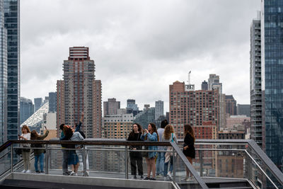 People on modern buildings in city against sky