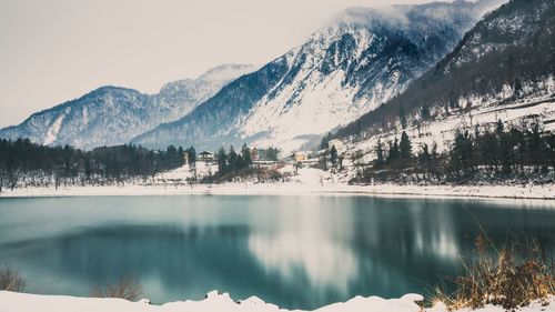 Scenic view of lake by snowcapped mountains against sky